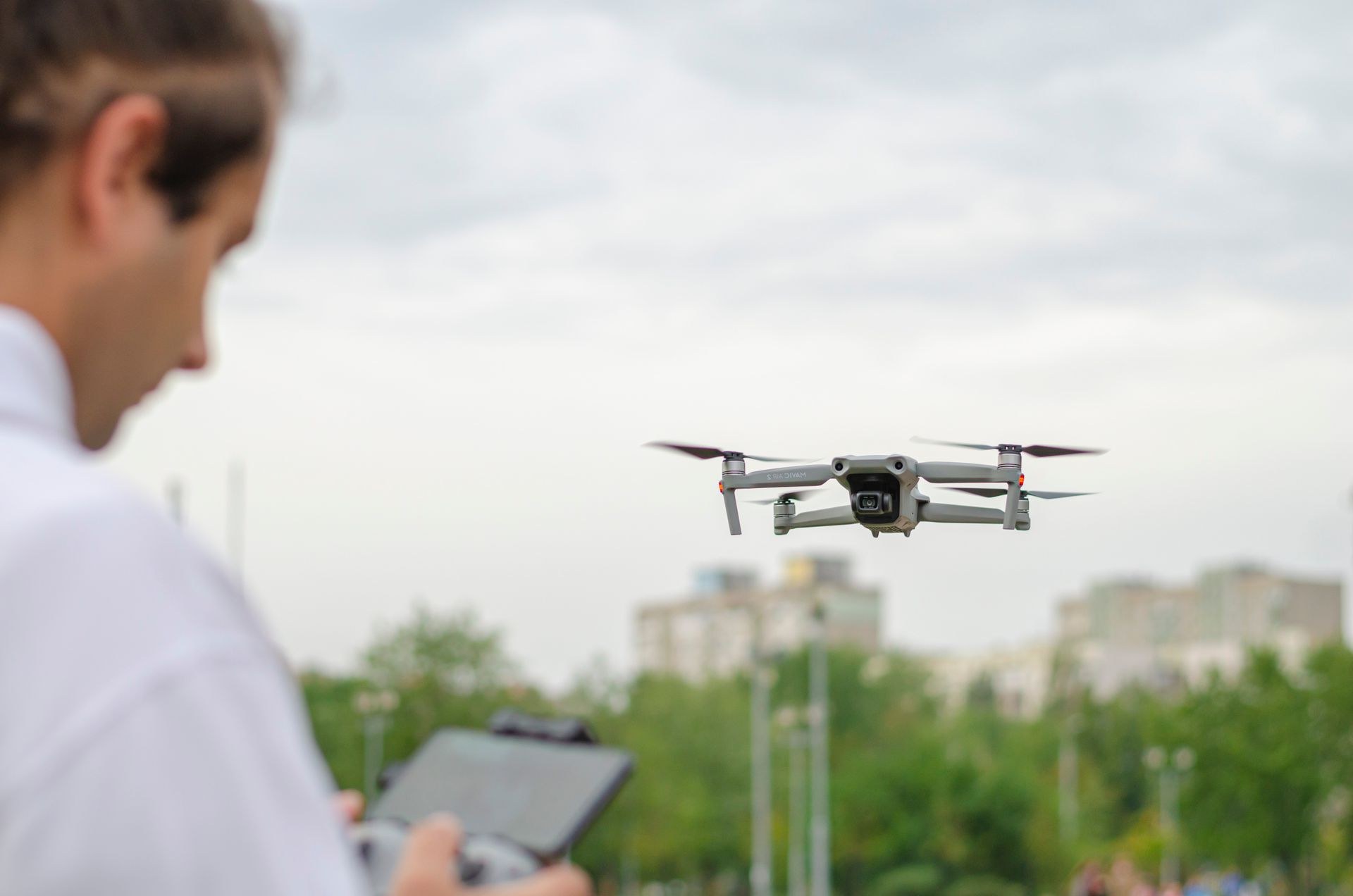 Pilot beobachtet eine Drohne im Schwebeflug vor urbaner Kulisse – Symbolbild digitaler Luftraum
